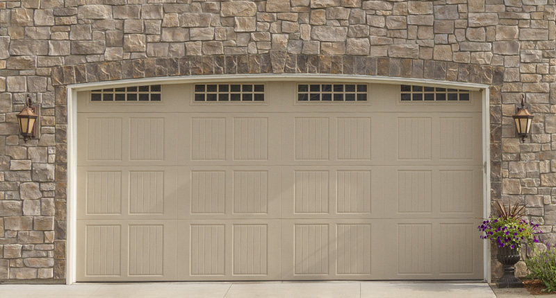 Castle accent stone on the exterior of a garage with different patterns going around the garage door in colors of grays and browns