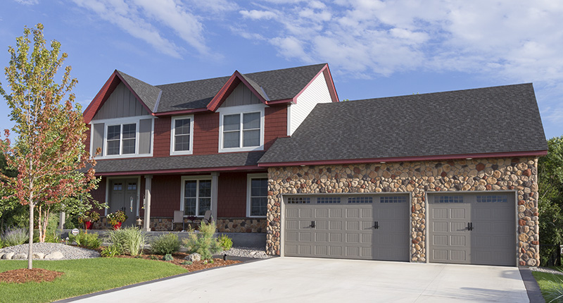 Blend of river rock stone in front of home with different sizes and colors of grays, tans and reds